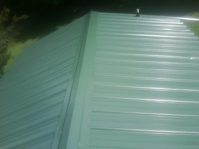 New green metal panels meeting at the ridge of a roof — Flat Roof Repair work by our crew in Luray