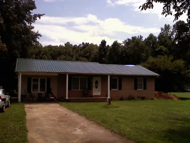 Dark green metal roof on a brick ranch with a covered porch in Luray