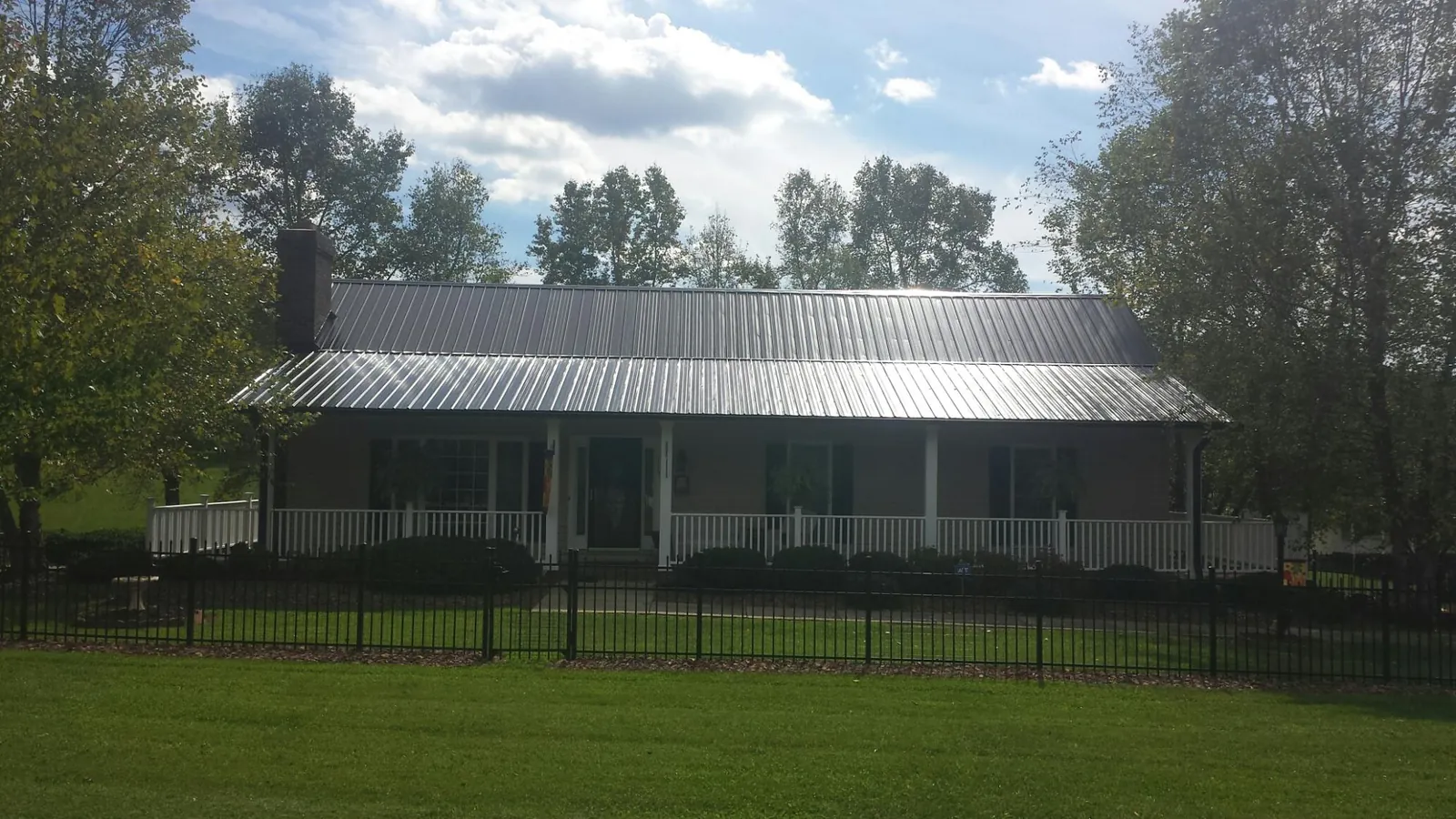 Gray metal roof on a brick ranch with a full width front porch — Gutter Guard Installation work by our crew in Luray