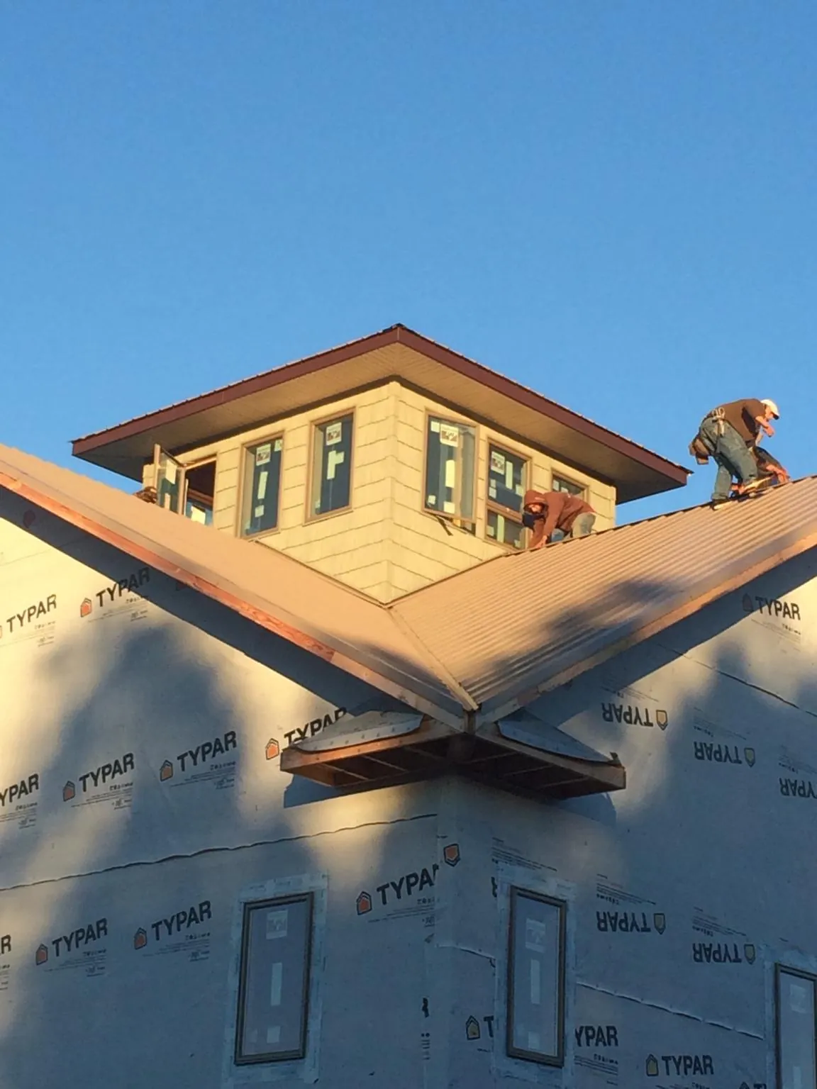 Roofers working around a rooftop cupola on a new metal roof at sunset — Roof Waterproofing in Luray by Roofing Brothers